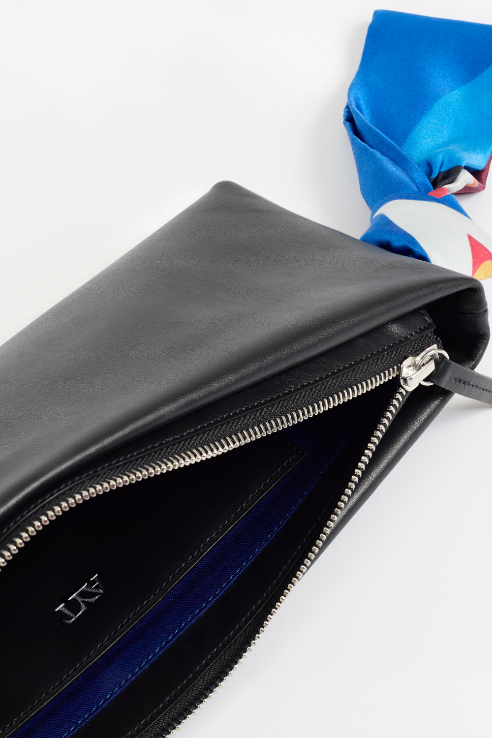 Details of AYT Studio 'LIEN' elongated leather pouch, made of smooth black leather with vibrant printed silk wrist strap, limited edition