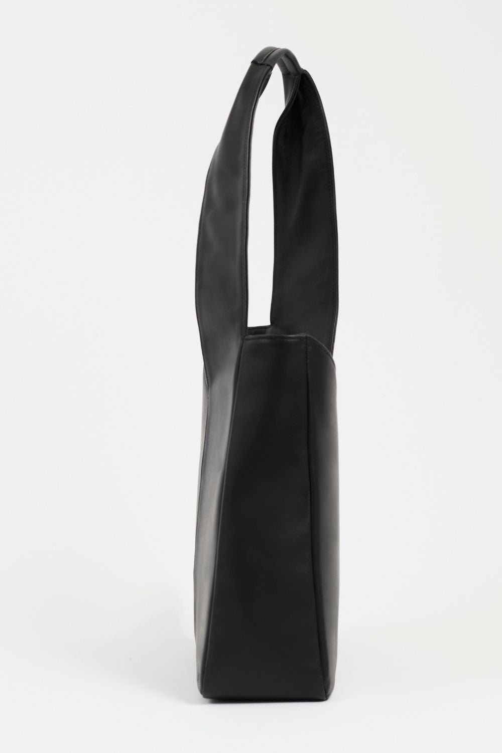 Side of AYT Studio 'FOULARD' tote bag made of black Italian leather and lining with zipped interior pocket, metal key hook, and handle with sophisticated scarf detail