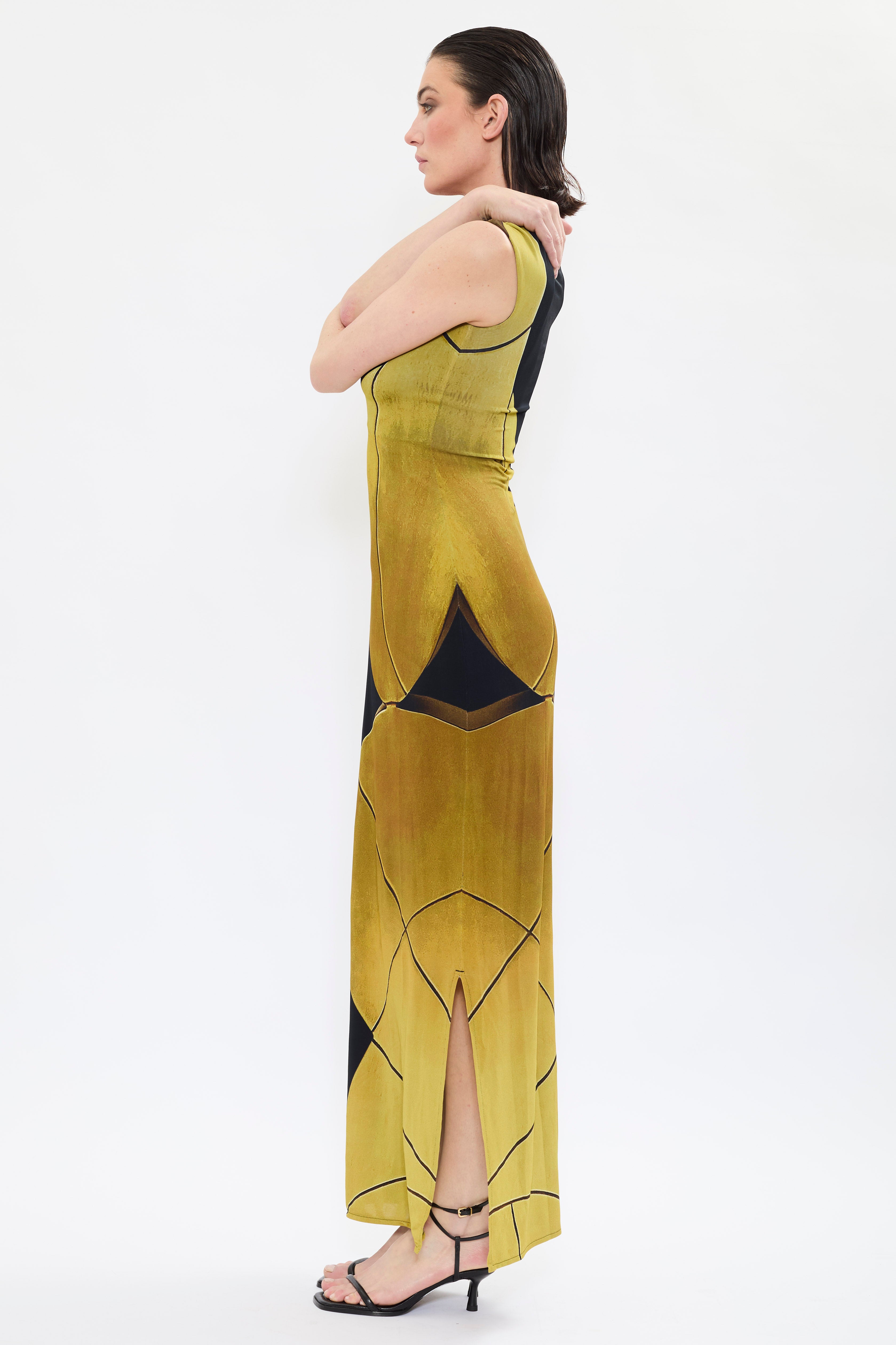Side view of AYT STUDIO x REMED, 'AURA' fluid viscose and elastane maxi dress with asymmetrical shoulder and side slits in printed black and gold, inspired by 'Femme & sphère.'