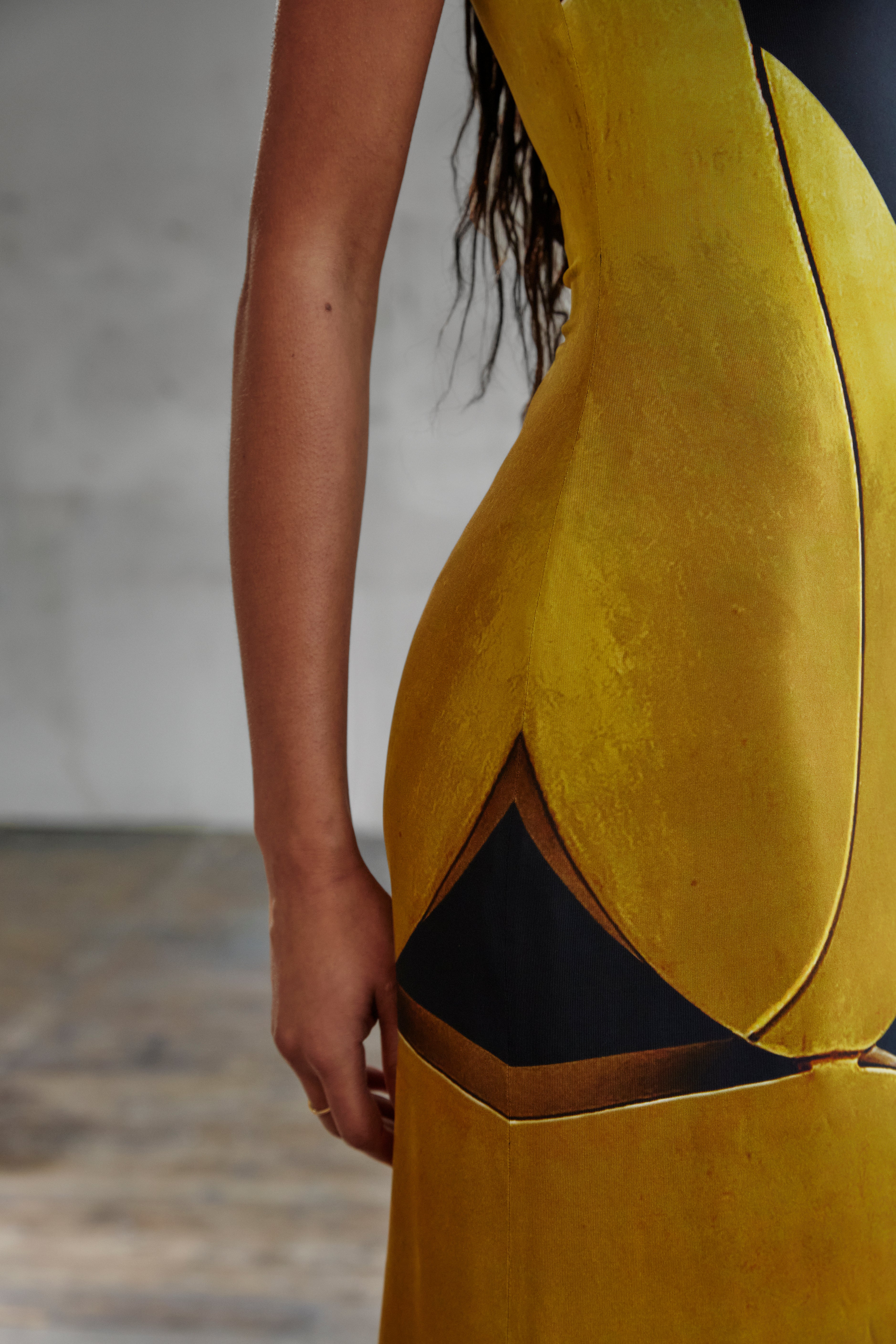 Details, print, and design of AYT STUDIO x REMED, 'AURA' fluid viscose and elastane maxi dress with asymmetrical shoulder and side slits in printed black and gold, inspired by 'Femme & sphère.'