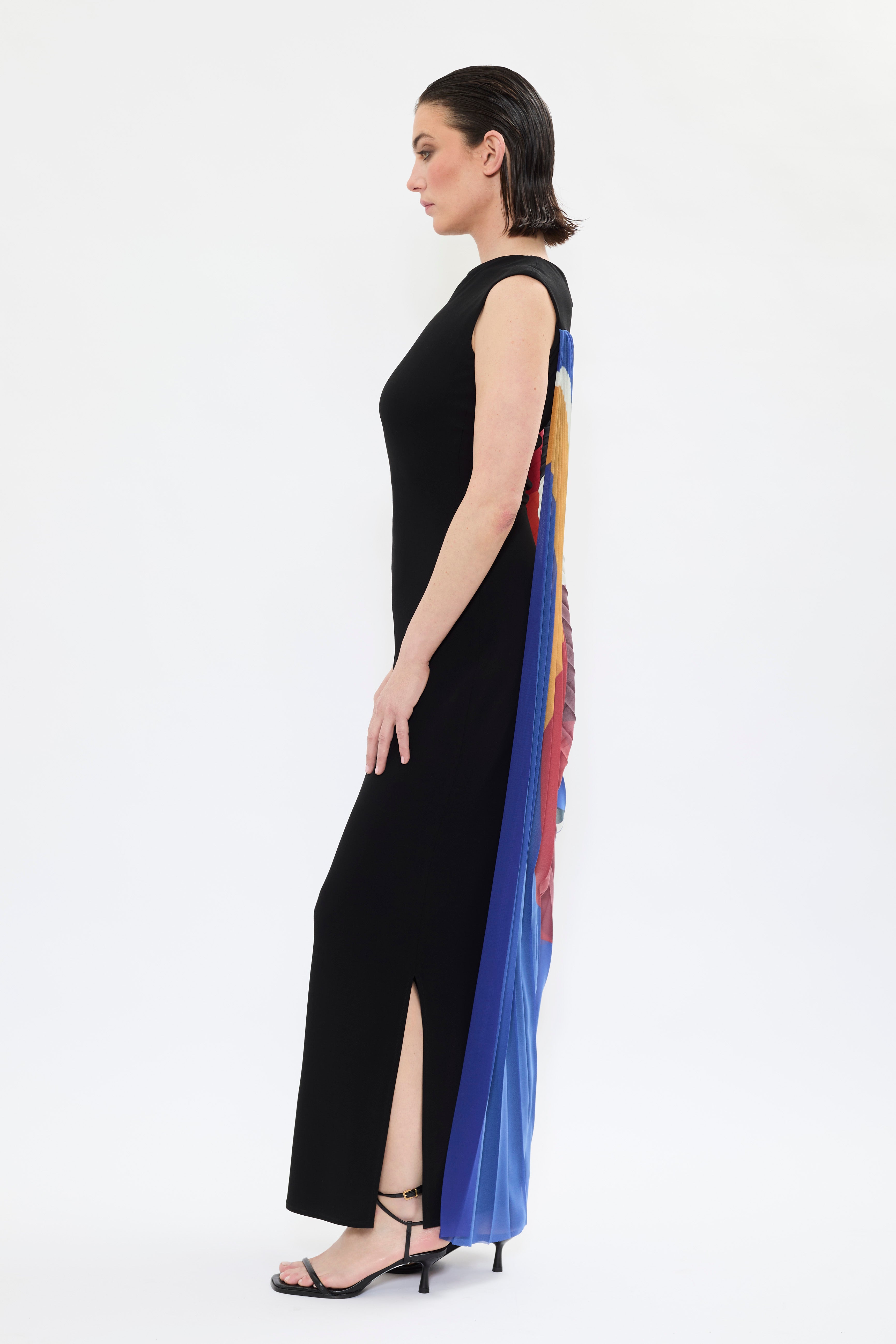Side profile of AYT STUDIO x French painter REMED 'ENVOL' long, maxi dress in a fluid jersey fabric with asymmetrical single sleeve, pleated, sculptural graphic patterned panel. Inspired by the painting 'Bel Envol.'