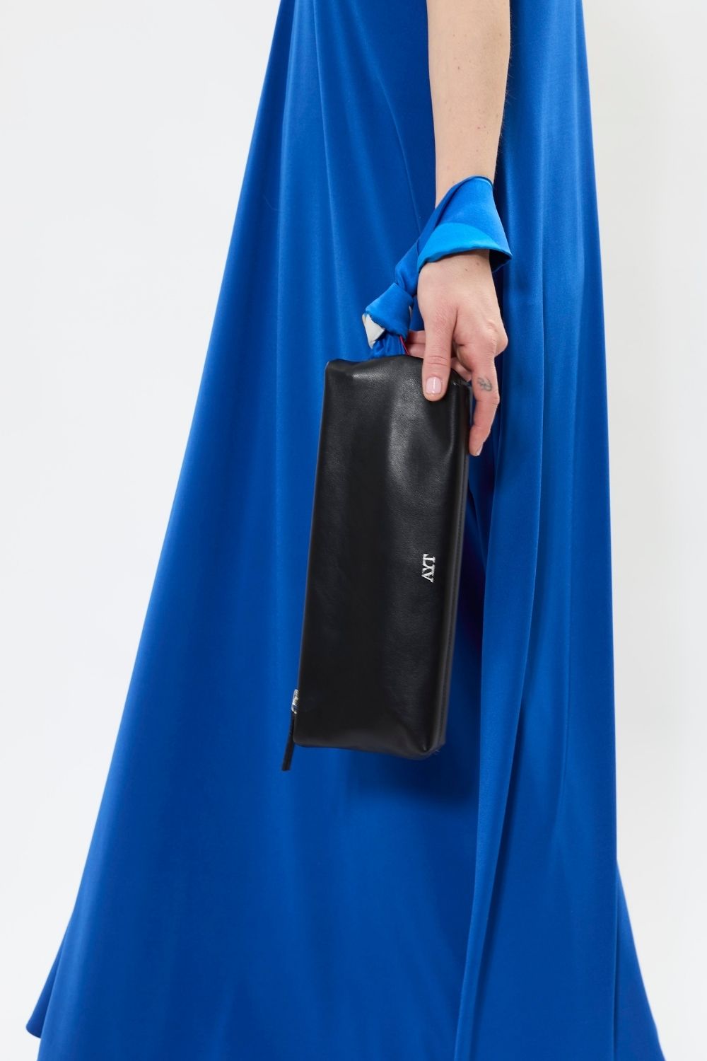 Woman holding AYT Studio x REMED 'FOULARD' Baguette, made of smooth black Italian leather with vibrant printed silk foulard handle, limited edition