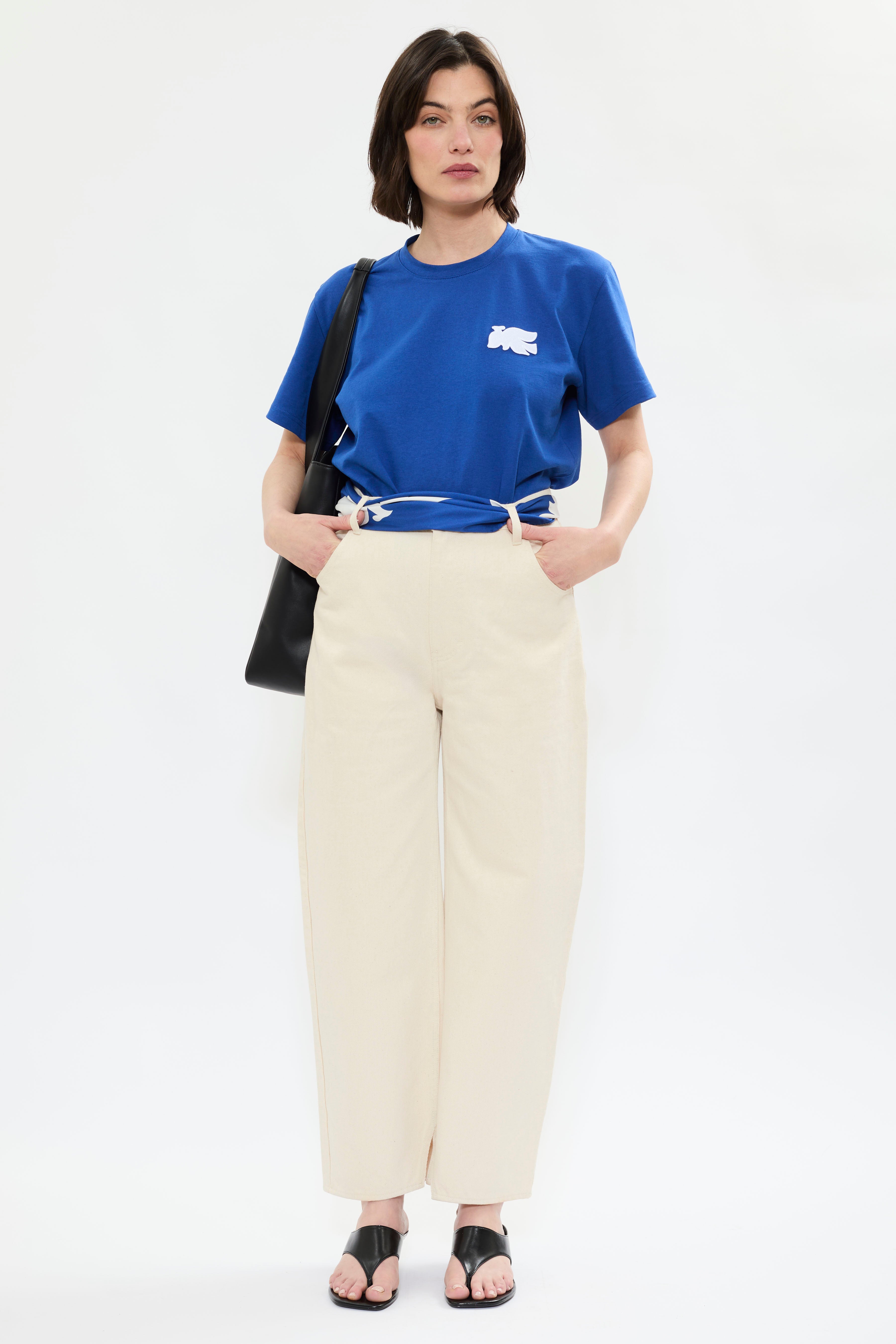 Front of AYT Studio x French artist REMED 'MIRAGE' blue 100% organic cotton T-shirt  with straight fit, round neckline, and blue bird embroidery inspired by Remed's painting 'Bel Envol.'