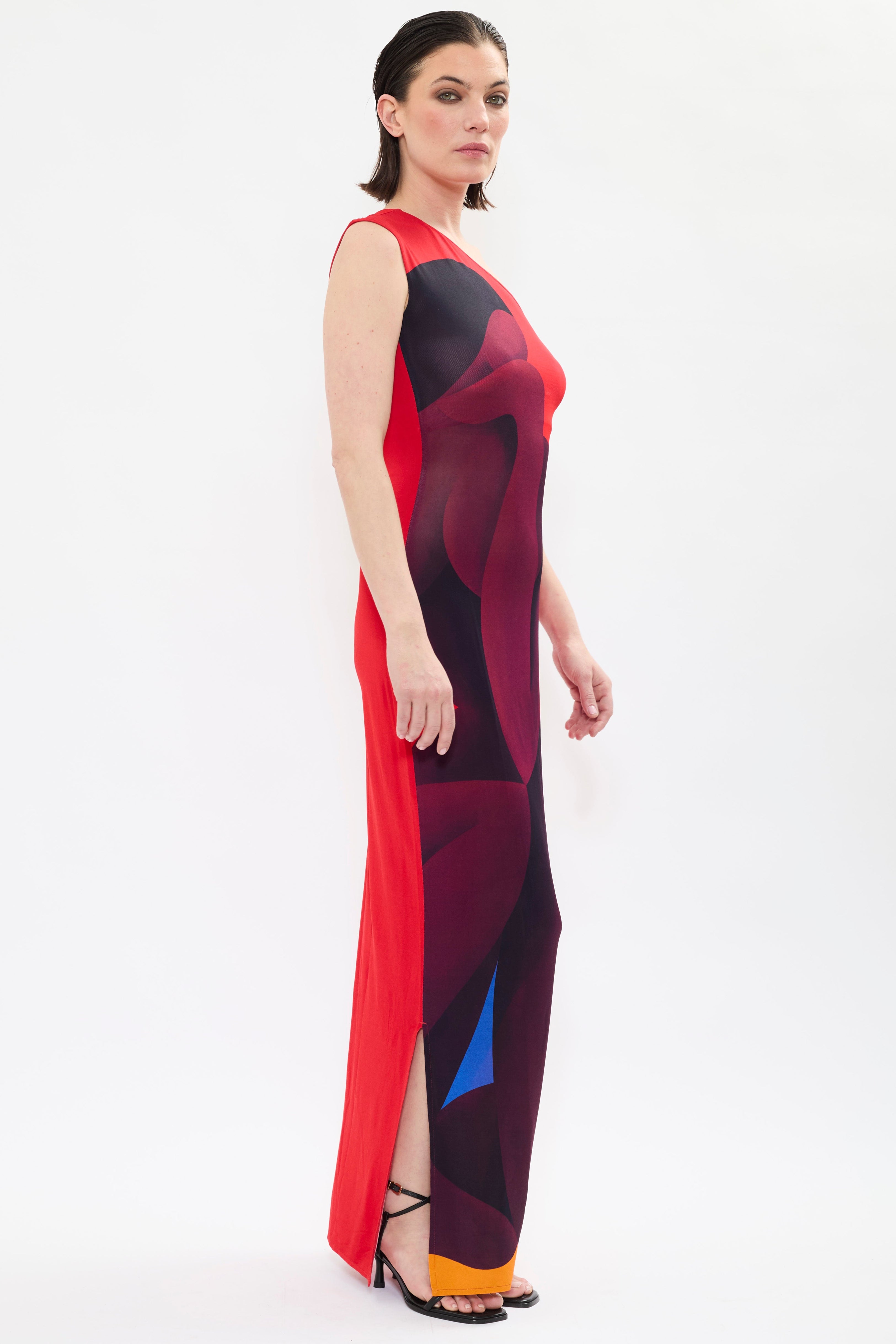 Side of AYT STUDIO x REMED ‘Muse’ one-shoulder maxi dress in fluid viscose with sculptural sleeve and red, black and orange bold artistic print inspired by 'El lago intimo.'