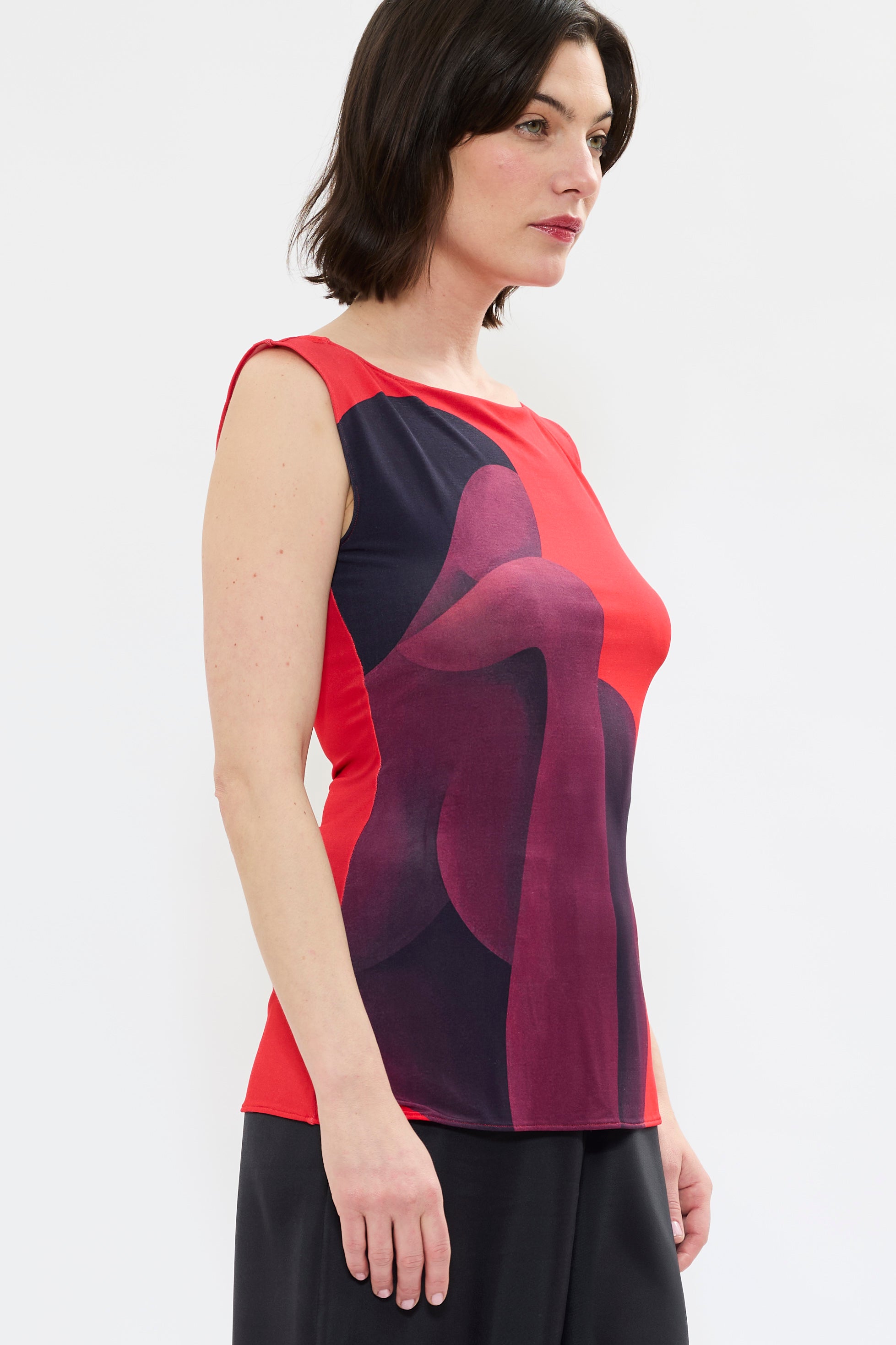 Profile of AYT STUDIO X REMED 'MUSE' lightweight viscose tank top in deep reds and black with a fitted, sleeveless silhouette, and boat neckline that highlight the elegance of the cut with a bold artistic print.