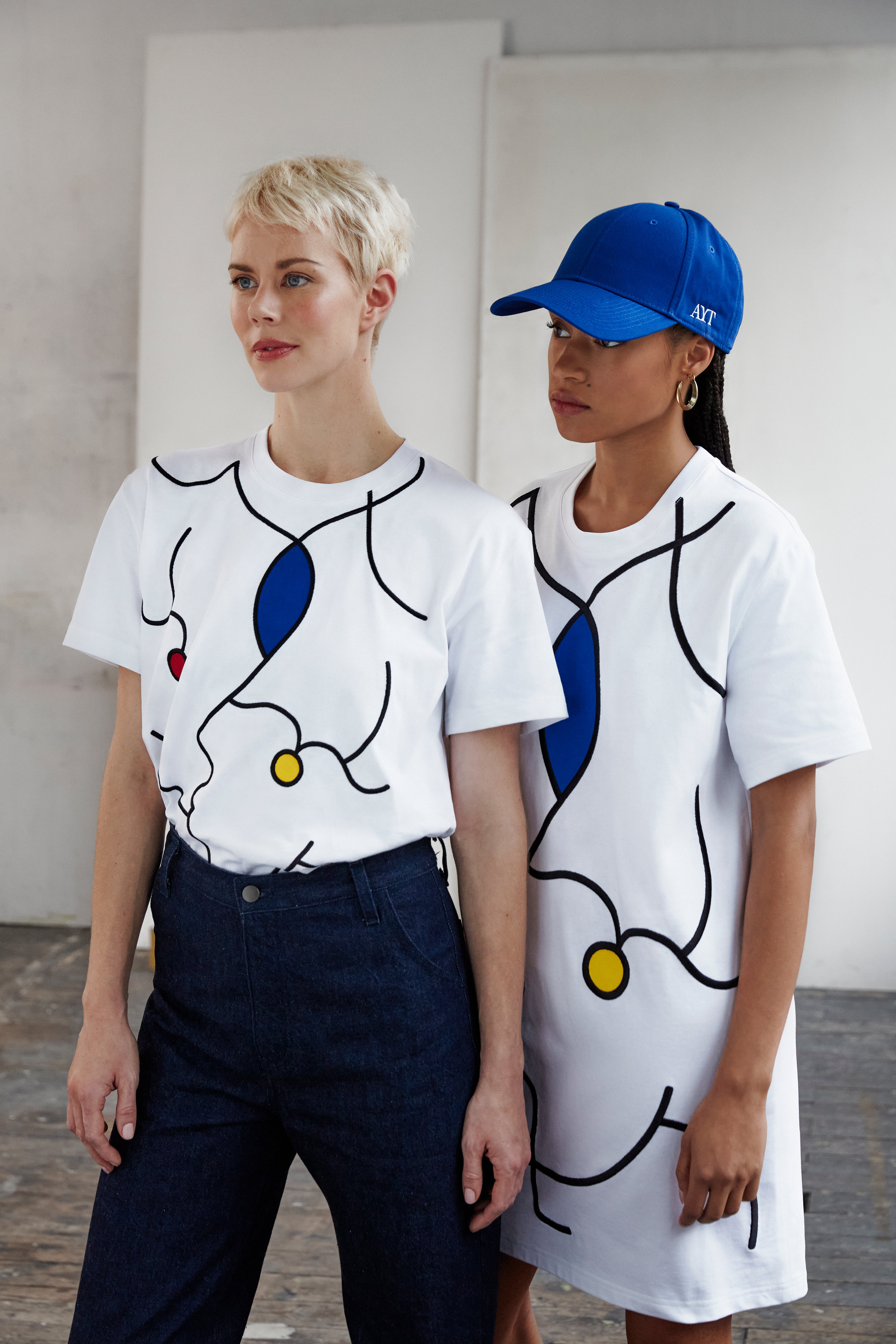 Models wearing AYT Studio x French painter REMED T-shirt in 100% organic cotton embellished in line art designs with straight oversized fit and round neckline that are versatile for day-to-night. Inspired by 'Oscillant silence, si dense.'