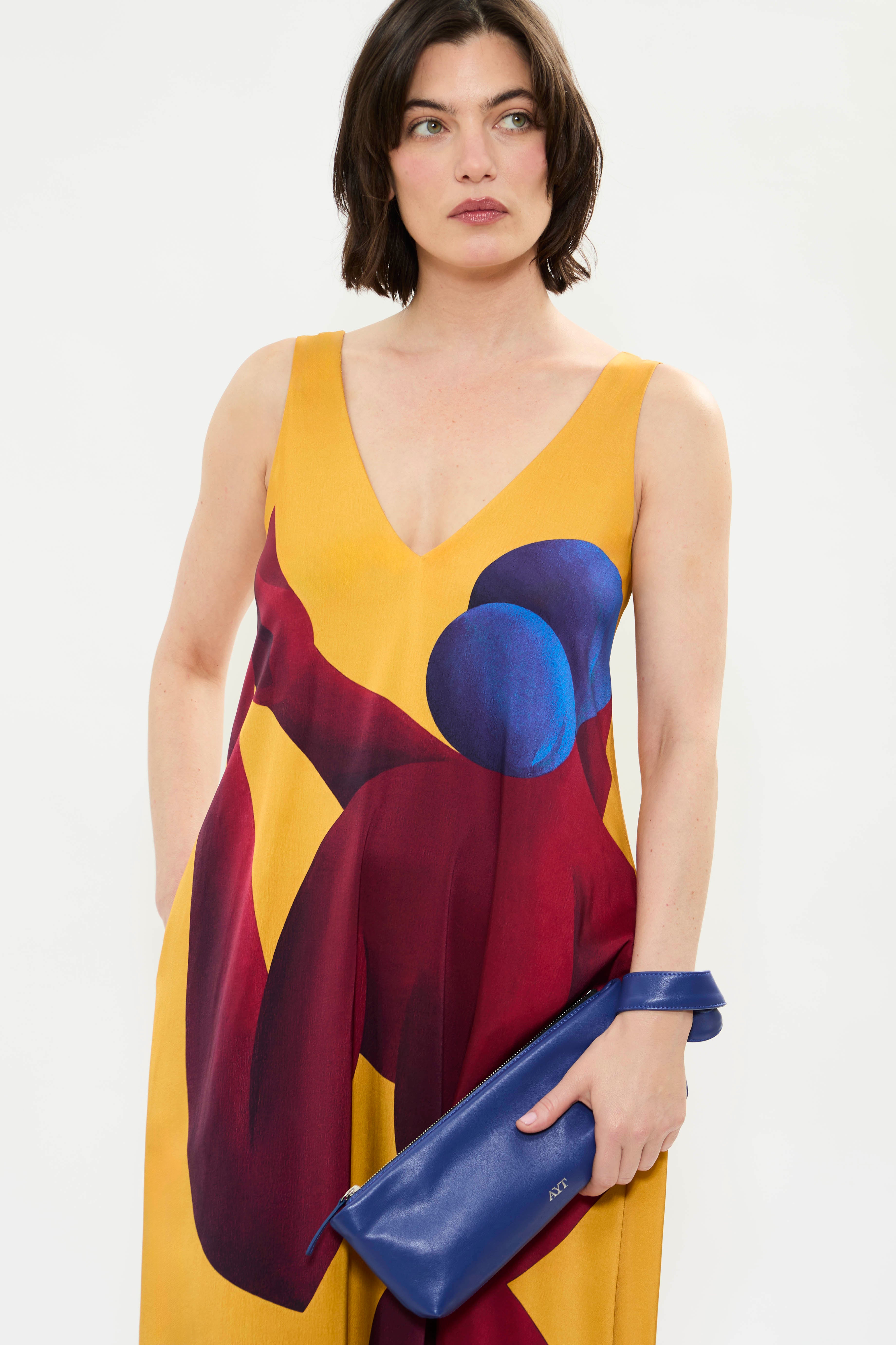 Close up of AYT Studio x French artist REMED 'SORORITY' fluid, vibrant yellow printed dress in viscose and elastane with punging V-neck front and back and discreet side pockets. Inspired by REMED's 'Bain de sable.'