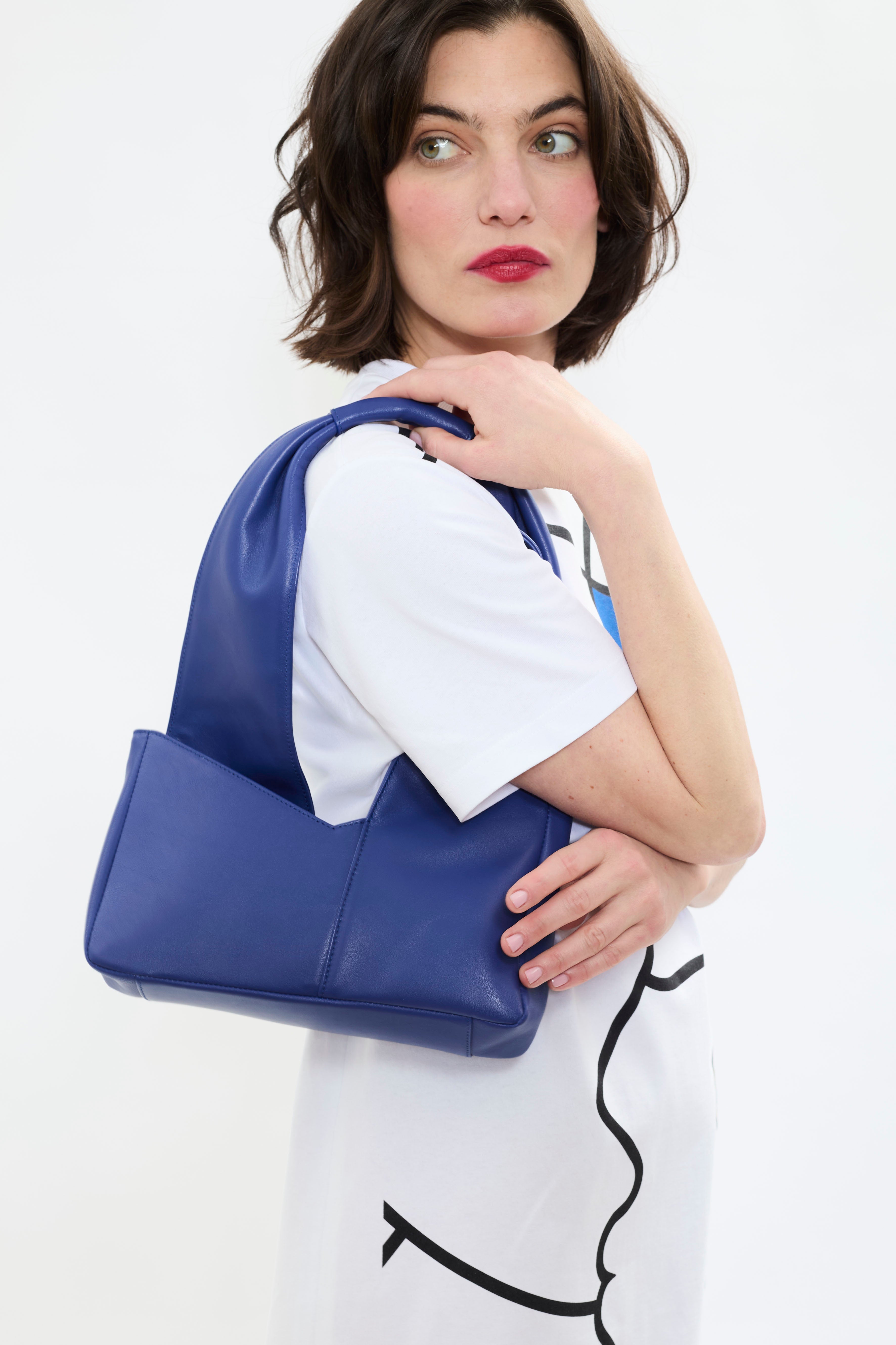 Model styling AYT Studio 'Dual' tote bag made of blue Italian leather and lining with full-length zipper and handle with sophisticated scarf detail for a minimalist yet distinctive look