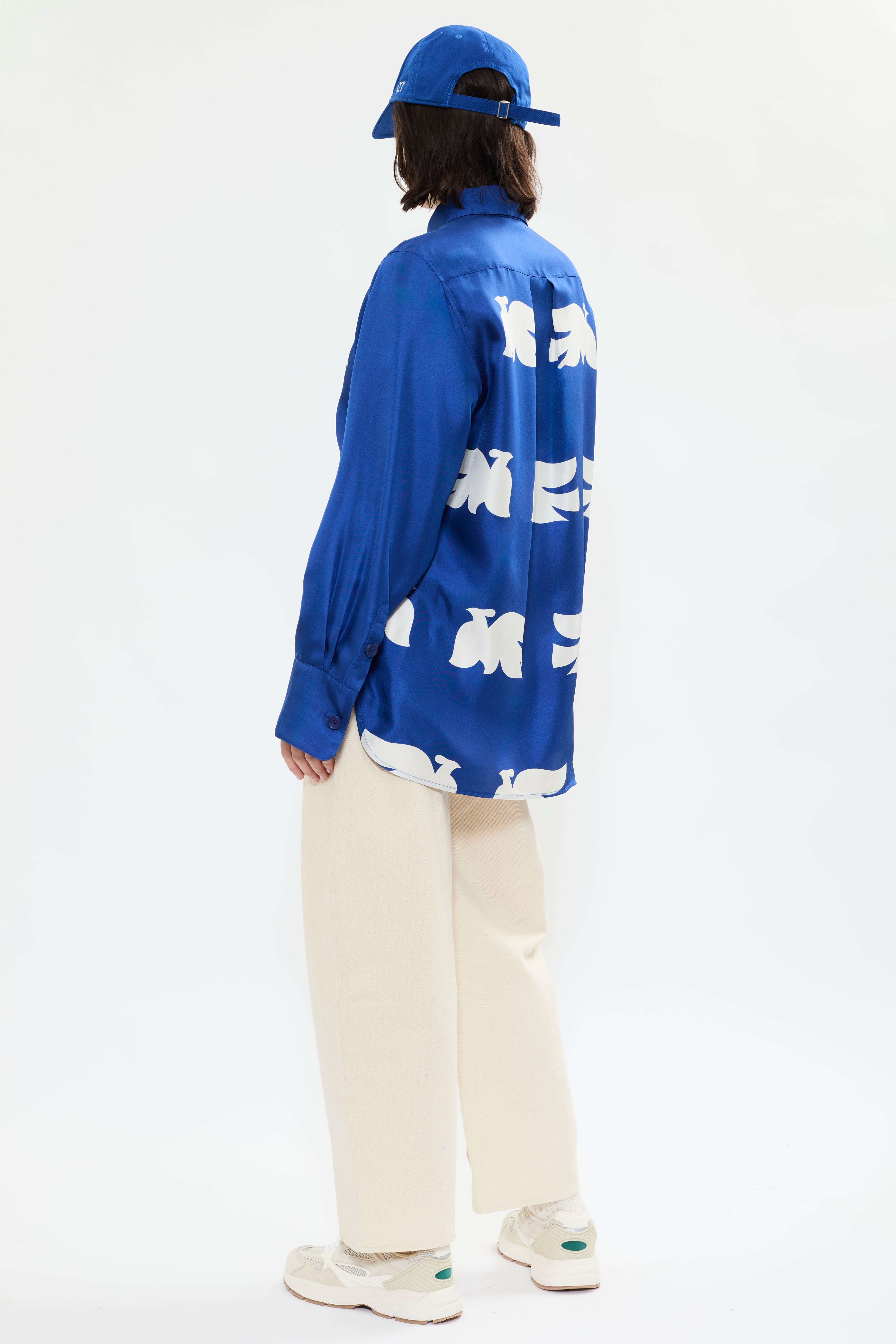 Rear view of AYT Studio x French artist REMED 'CLOUD OF BIRDS' 100% twill silk button down shirt with structured collar, long sleeves. Lightweight and versatile for day-to-night, relaxed, unisex style. Inspired by REMED's 'Bel Envol.'