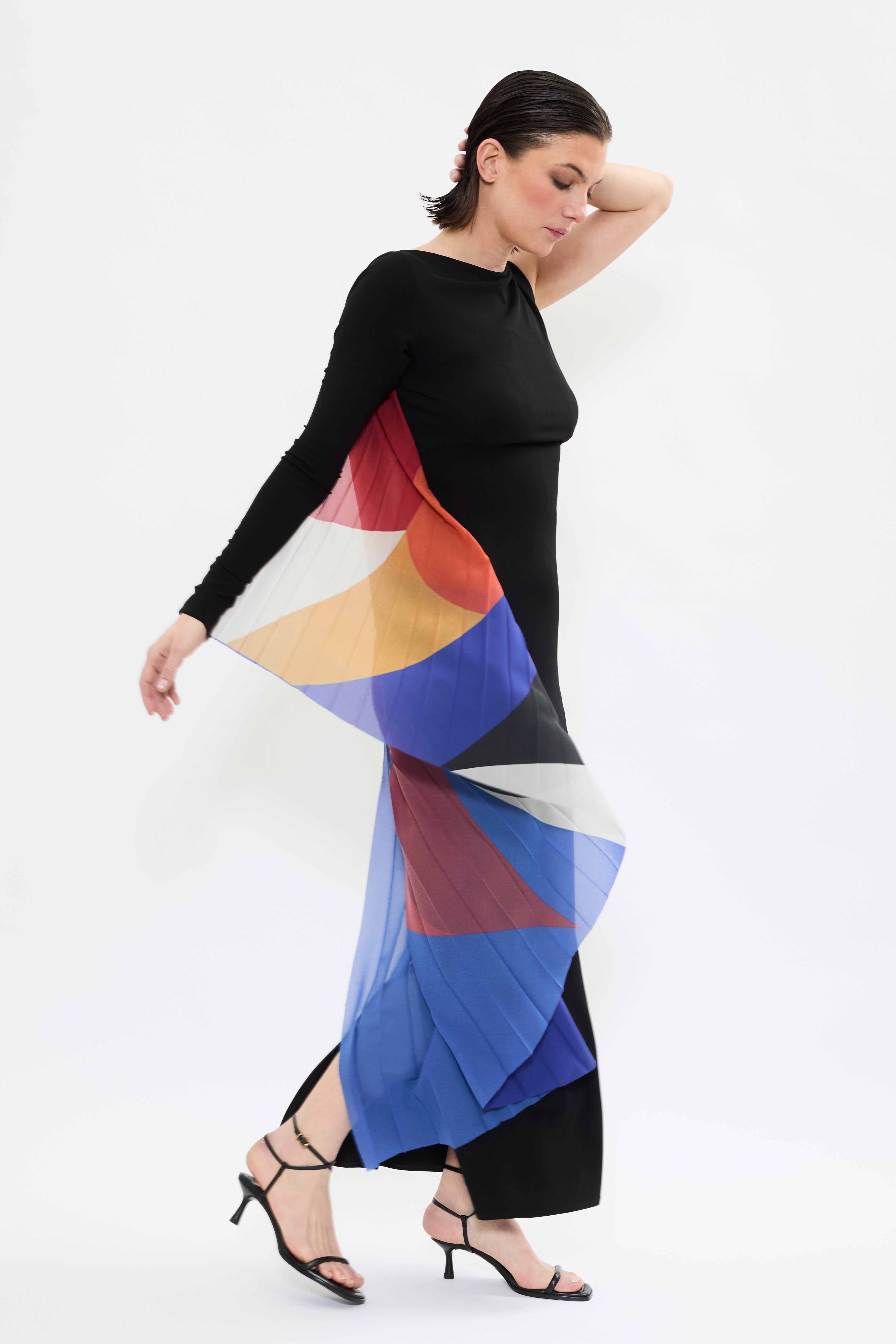 Model styled in AYT STUDIO x French painter REMED 'ENVOL' long, maxi dress in a fluid jersey fabric with asymmetrical single sleeve, pleated, sculptural graphic patterned panel. Inspired by the painting 'Bel Envol.'