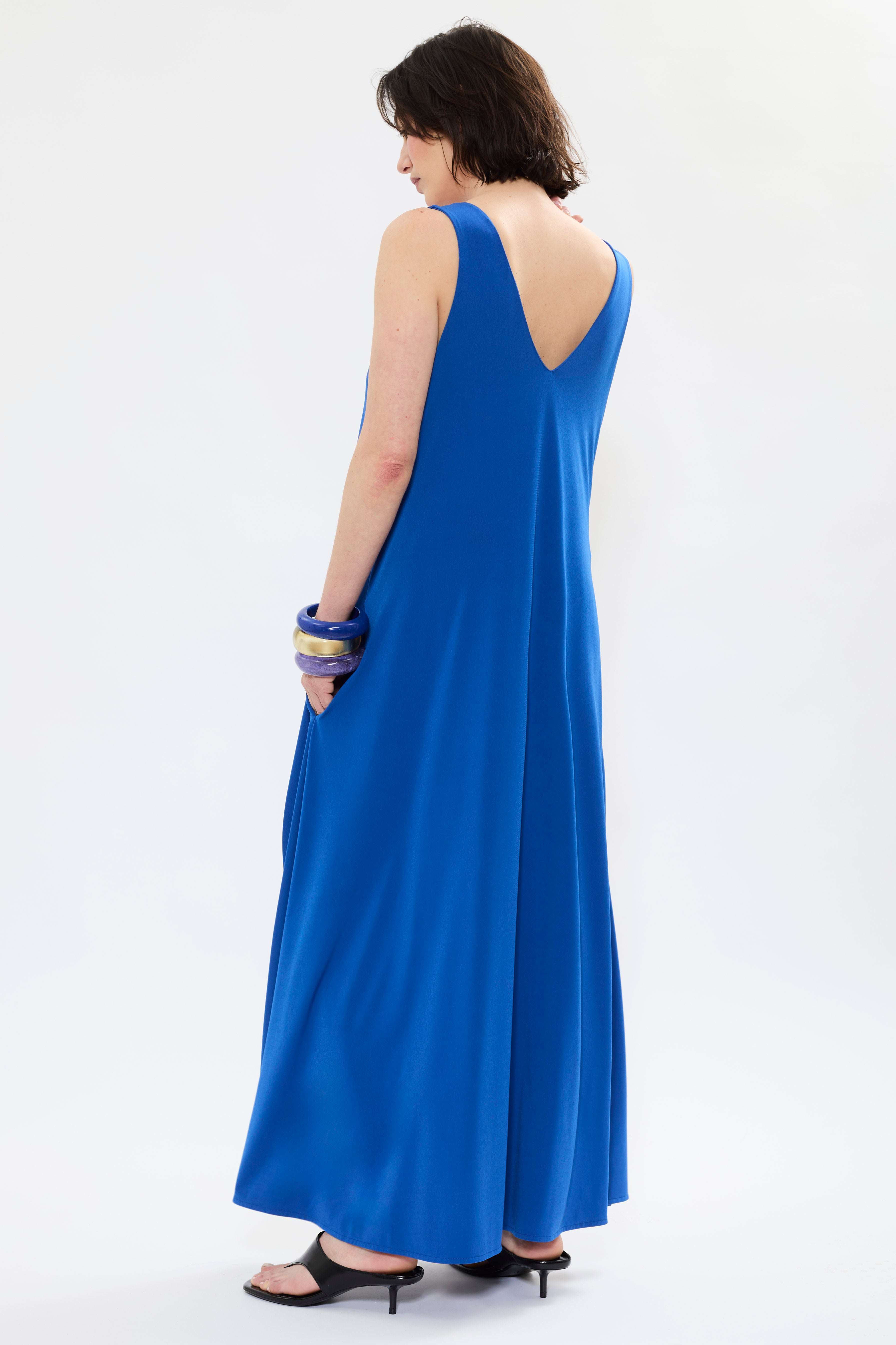 Rear of AYT Studio x French artist REMED 'MIRAGE' fluid blue dress in with plunging V-neck front and back, discreet side pockets, and white bird embroidery. Inspired by REMED's 'Ben Envol.'