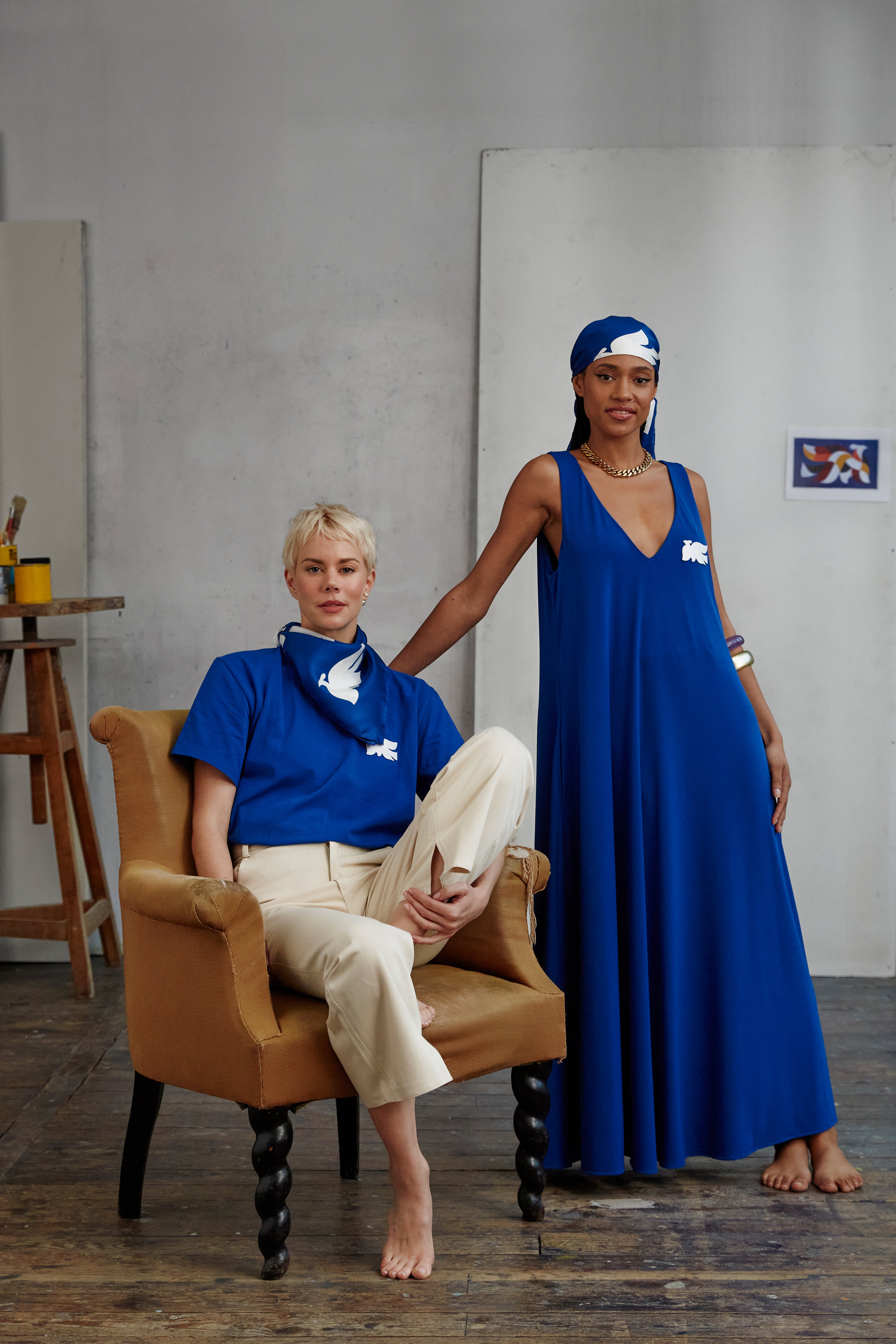 Model wearing AYT Studio x French artist REMED 'MIRAGE' fluid blue dress in with plunging V-neck front and back, discreet side pockets, and white bird embroidery. Inspired by REMED's 'Ben Envol.'