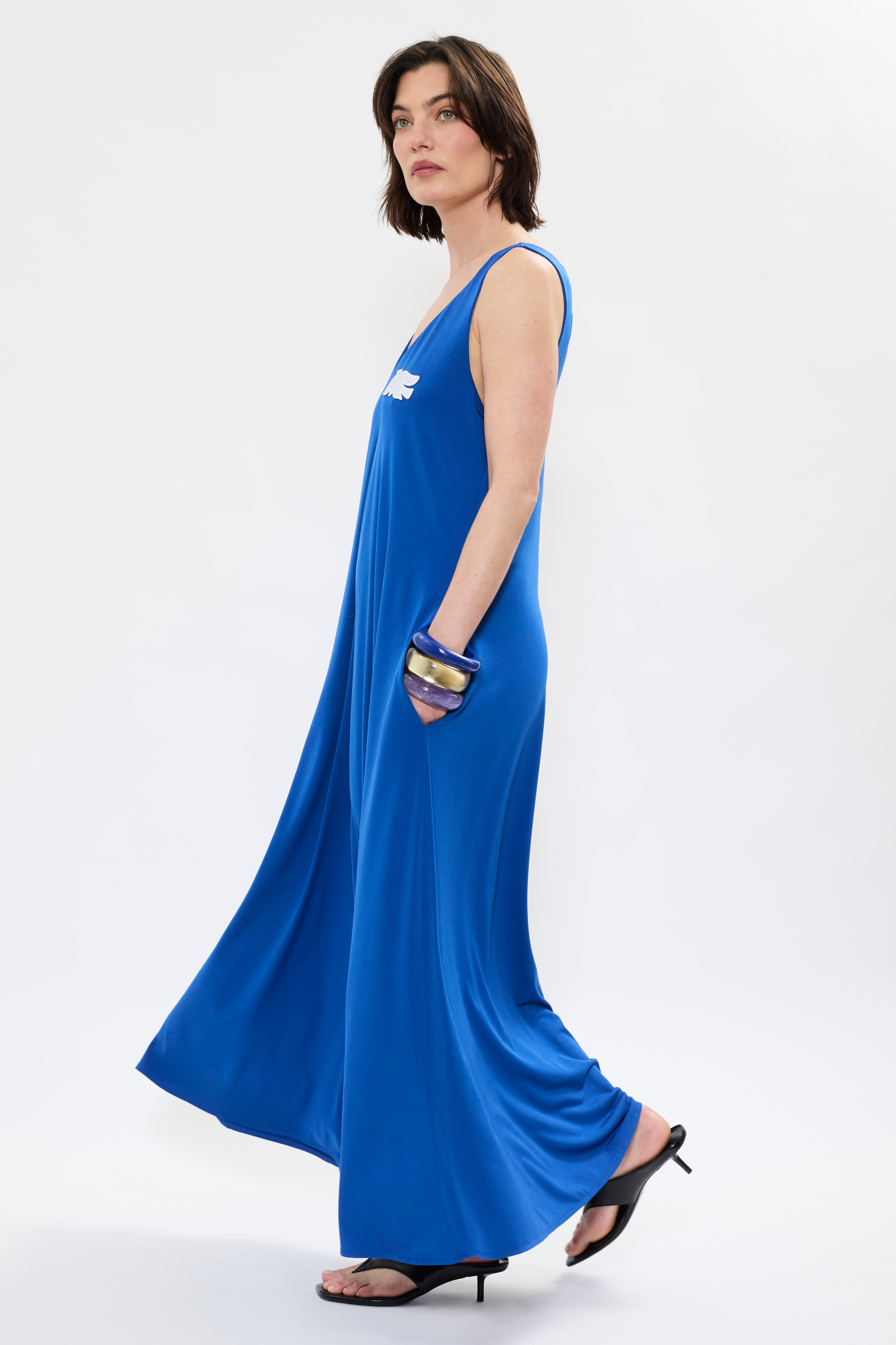 Side of AYT Studio x French artist REMED 'MIRAGE' fluid blue dress in with plunging V-neck front and back, discreet side pockets, and white bird embroidery. Inspired by REMED's 'Ben Envol.'