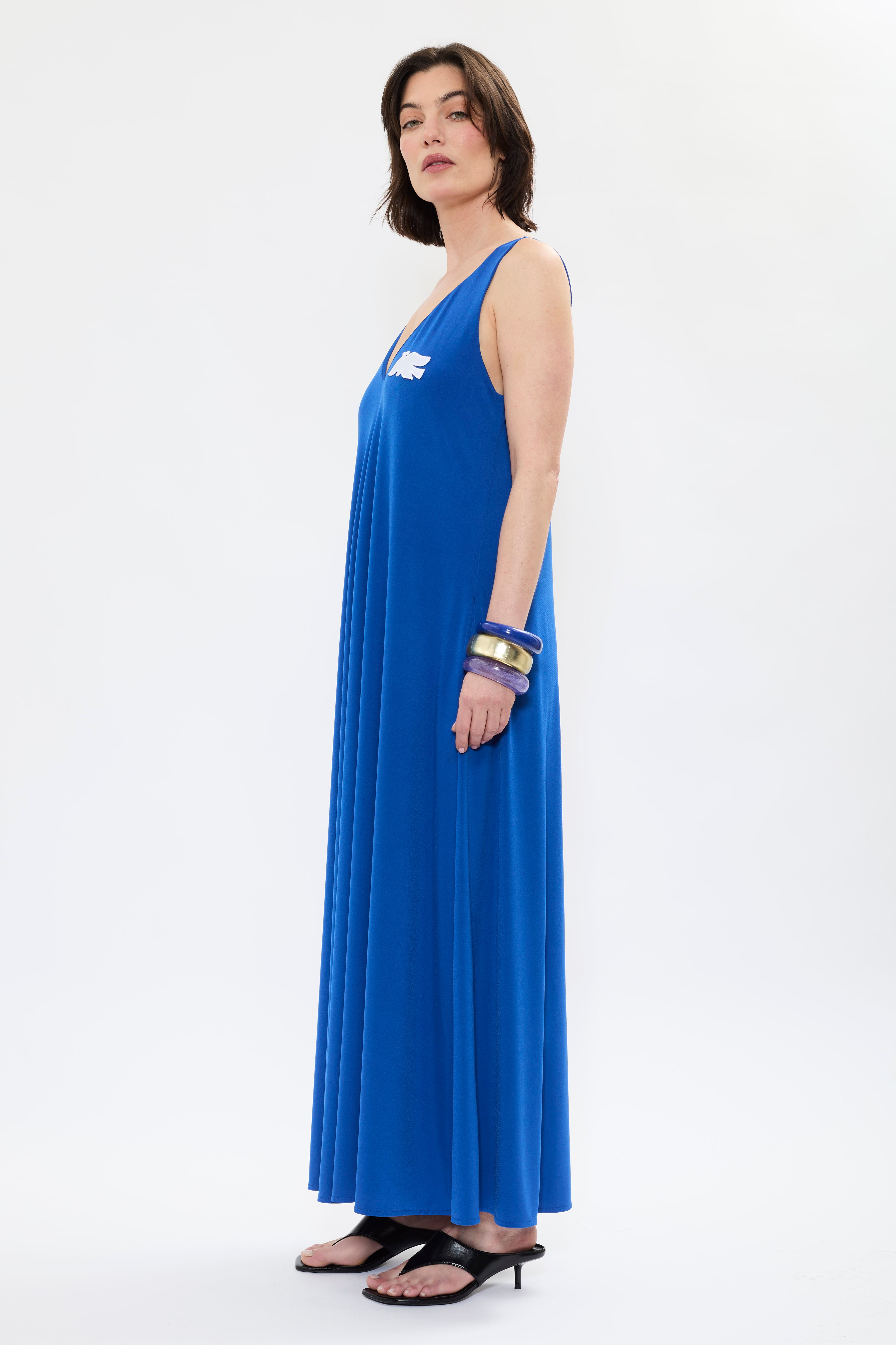 Profile of AYT Studio x French artist REMED 'MIRAGE' fluid blue dress in with plunging V-neck front and back, discreet side pockets, and white bird embroidery. Inspired by REMED's 'Ben Envol.'