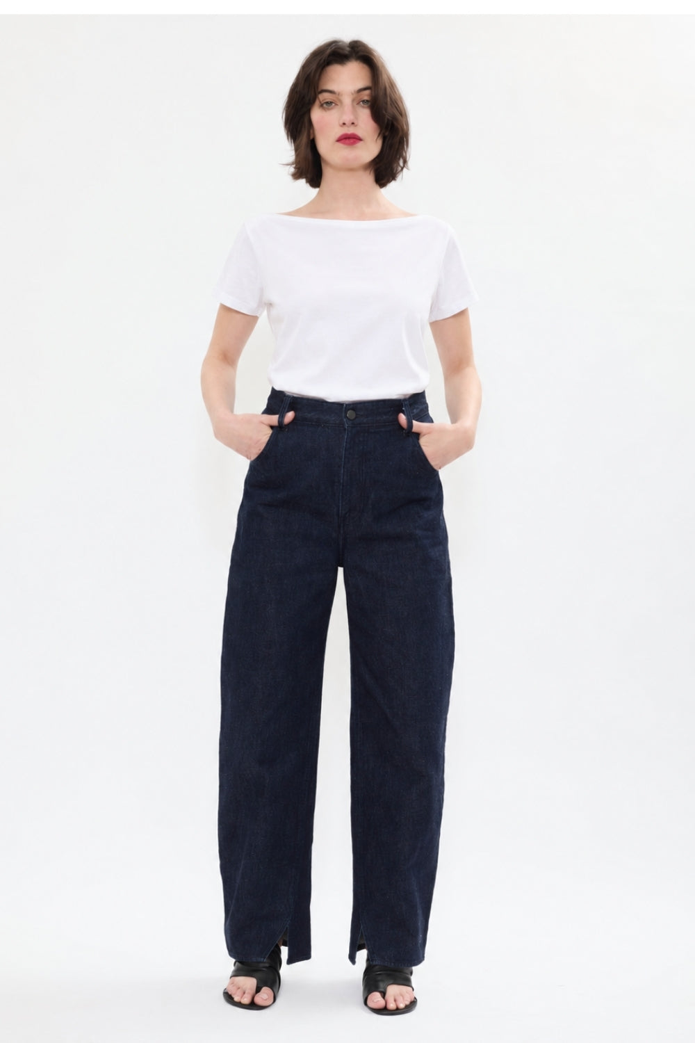 AYT STUDIO 'TRIBE' high-rise curved straight leg 100% recycled cotton jeans in blue with signature AYT Studio logo, ankle slit detail, and functional front and back pockets.